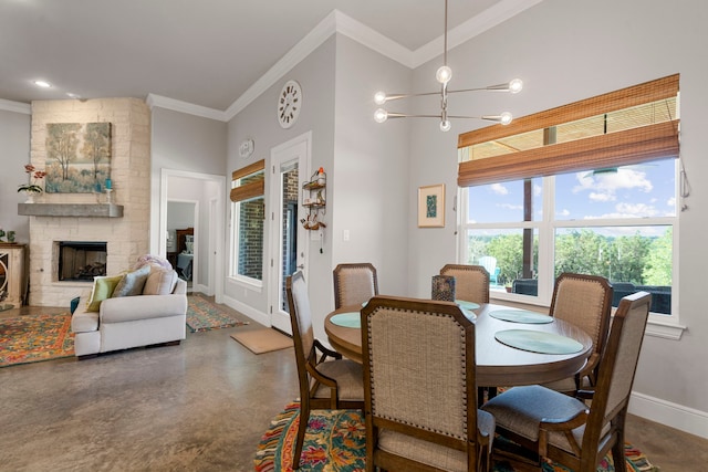 dining area featuring finished concrete flooring, ornamental molding, a stone fireplace, and baseboards
