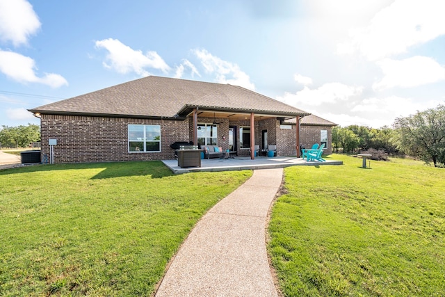 back of property with brick siding, a shingled roof, a patio, outdoor lounge area, and a lawn