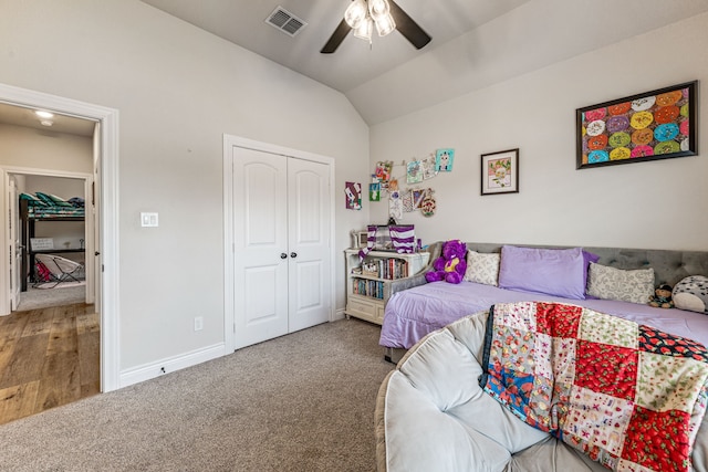 carpeted bedroom with lofted ceiling, visible vents, baseboards, a closet, and a ceiling fan