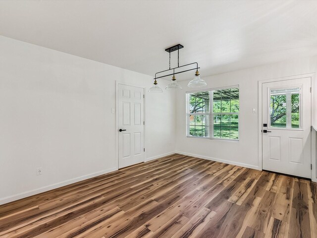 unfurnished dining area with wood finished floors and baseboards
