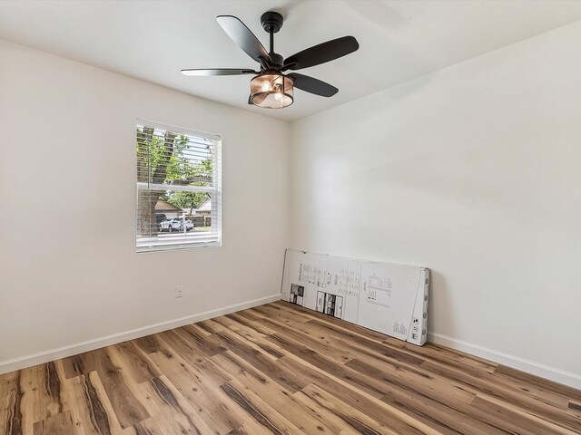 unfurnished room with wood finished floors, ceiling fan, and baseboards