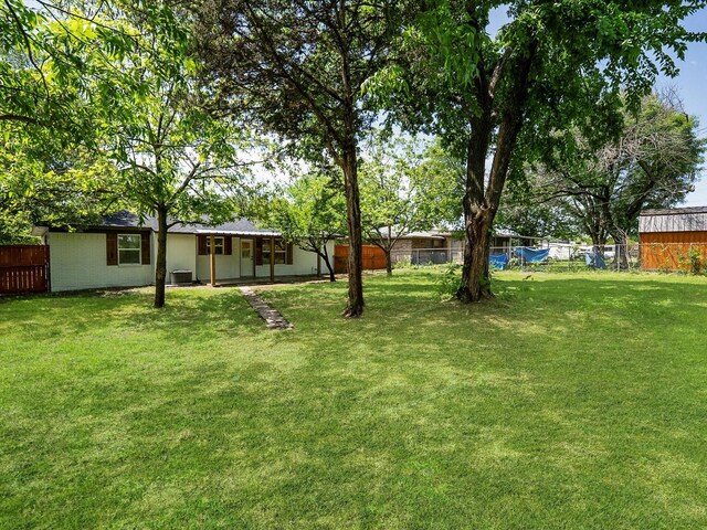 view of yard featuring central AC and fence