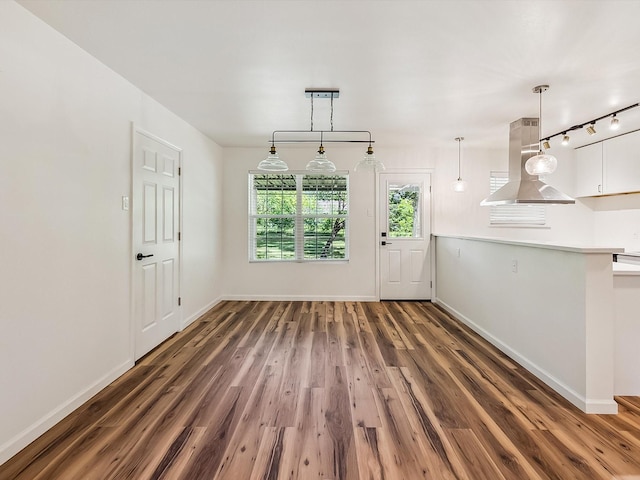 unfurnished dining area with baseboards and wood finished floors