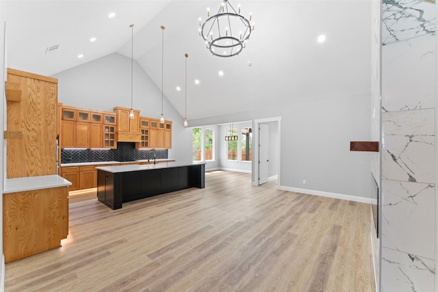 kitchen with an island with sink, light countertops, high vaulted ceiling, a chandelier, and open floor plan