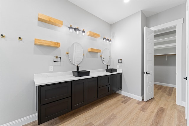 full bath with double vanity, baseboards, wood finished floors, and a sink
