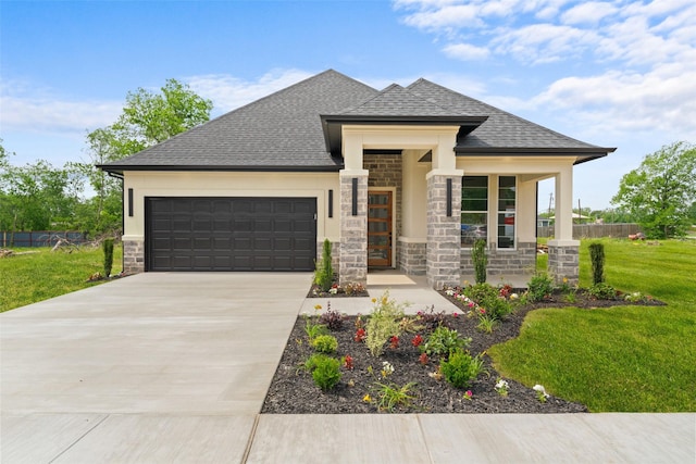 prairie-style house featuring a front lawn, stone siding, a shingled roof, concrete driveway, and an attached garage