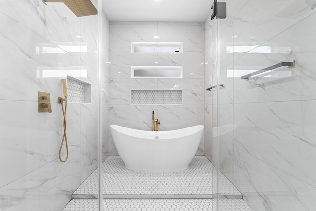 bathroom with a marble finish shower, tile patterned floors, a freestanding tub, and tile walls