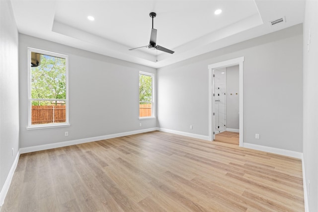 unfurnished room with visible vents, a ceiling fan, a raised ceiling, and light wood finished floors
