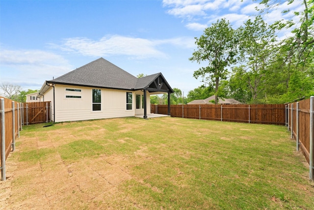 rear view of property featuring a yard, a fenced backyard, and roof with shingles