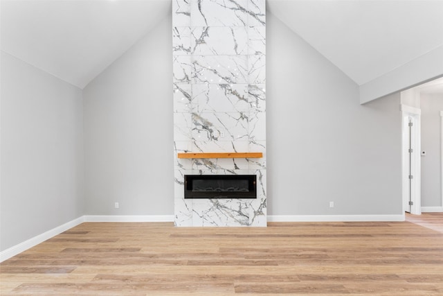unfurnished living room with baseboards, a premium fireplace, high vaulted ceiling, and wood finished floors