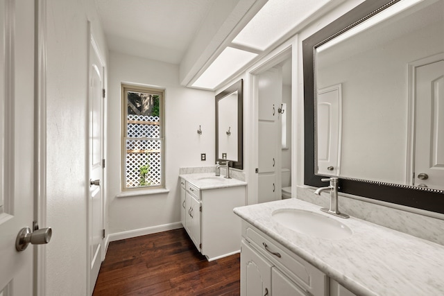 bathroom featuring wood finished floors, two vanities, and baseboards