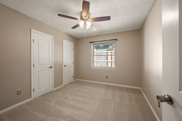unfurnished bedroom with a textured ceiling, carpet flooring, ceiling fan, and baseboards