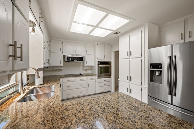 kitchen with appliances with stainless steel finishes, a sink, and white cabinetry