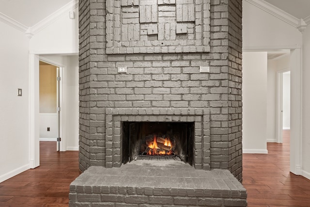 detailed view of crown molding, a fireplace, wood finished floors, and baseboards