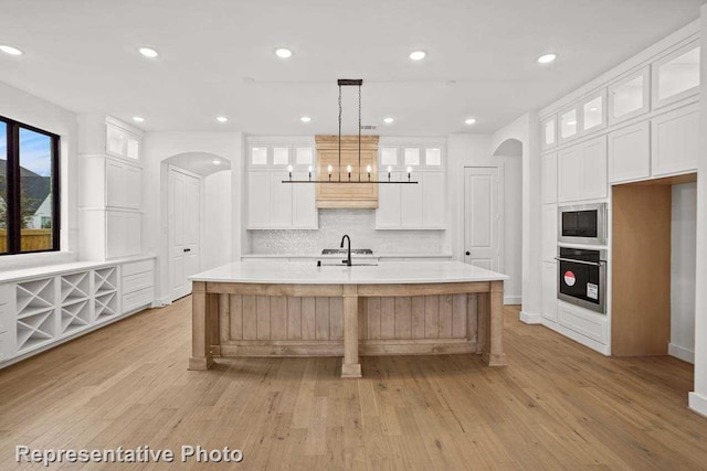 kitchen featuring stainless steel appliances, light wood-style flooring, and arched walkways