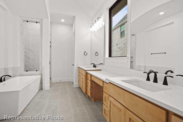 bathroom featuring double vanity, a soaking tub, recessed lighting, and a sink