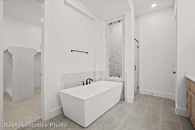 bathroom with recessed lighting, a shower stall, vanity, a freestanding tub, and baseboards