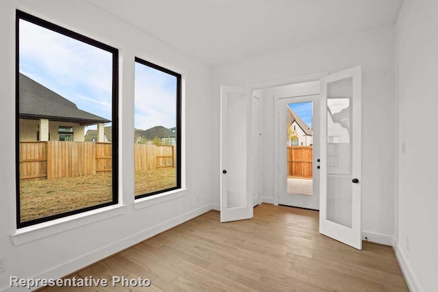 spare room with french doors, wood finished floors, and baseboards