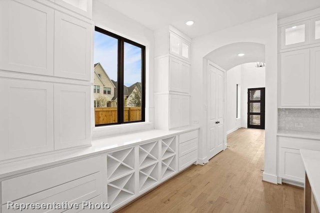 hall with recessed lighting, light wood finished floors, baseboards, and arched walkways