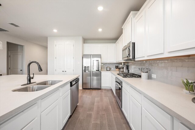 kitchen with stainless steel appliances, light wood-style floors, white cabinetry, light countertops, and backsplash