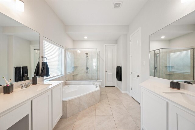 full bathroom featuring healthy amount of natural light, ensuite bath, and two vanities