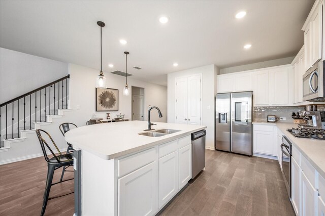 kitchen with appliances with stainless steel finishes, a sink, a kitchen breakfast bar, backsplash, and light countertops