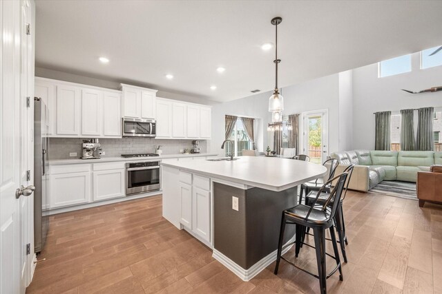 living area with a towering ceiling, a ceiling fan, wood finished floors, and baseboards