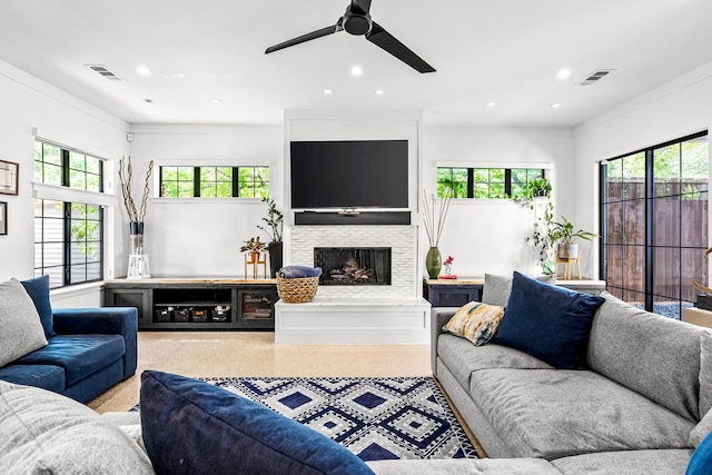 living room featuring visible vents, a ceiling fan, a fireplace with raised hearth, and recessed lighting
