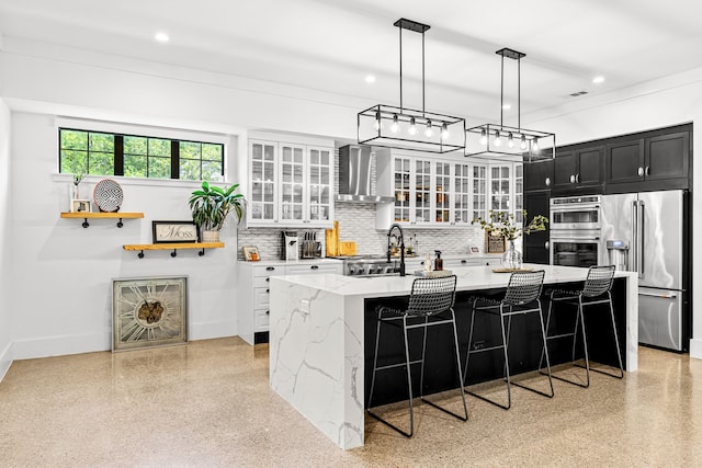 kitchen with wall chimney range hood, appliances with stainless steel finishes, recessed lighting, light speckled floor, and dark cabinetry