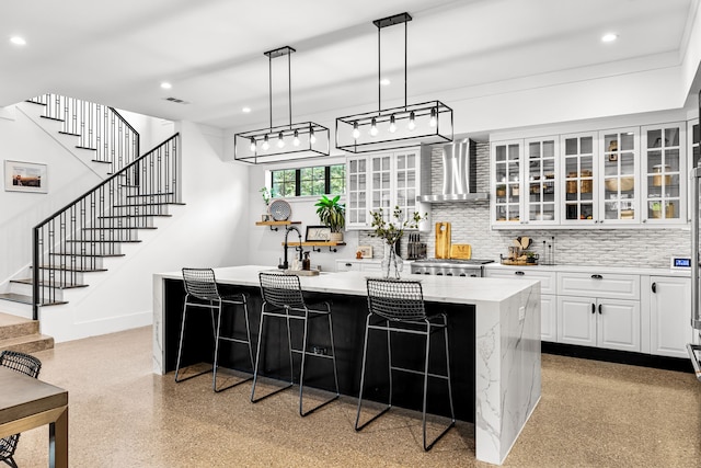kitchen with white cabinetry, decorative backsplash, a center island, wall chimney exhaust hood, and light speckled floor