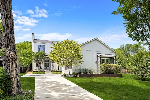 view of front of home with a front yard, board and batten siding, and a chimney