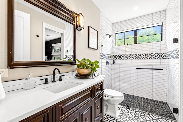 full bathroom with tiled shower, toilet, and vanity