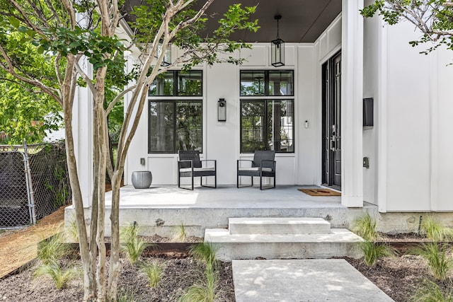 doorway to property with covered porch and fence