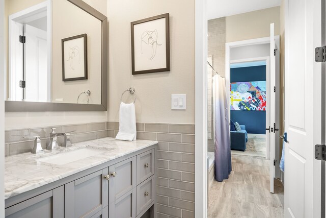 full bath with tile walls, wood finished floors, and vanity
