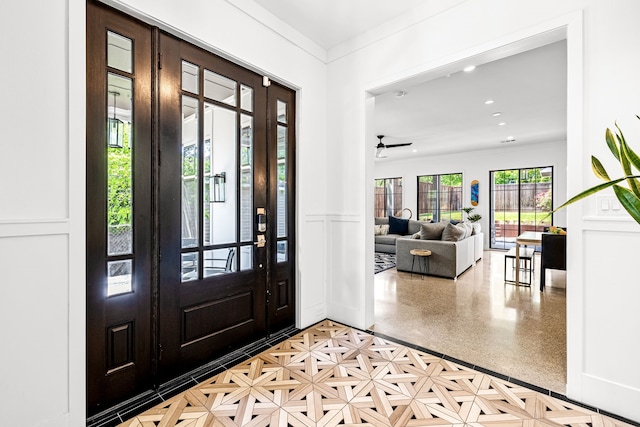entrance foyer with recessed lighting, a wainscoted wall, crown molding, and a decorative wall