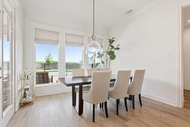 dining area with baseboards, visible vents, light wood-style floors, and crown molding