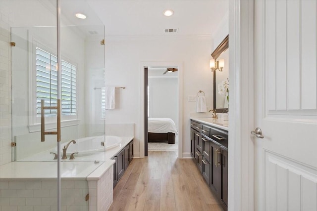ensuite bathroom featuring connected bathroom, visible vents, a bath, wood finished floors, and vanity