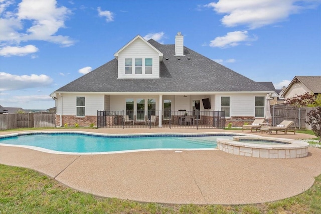 view of pool with fence, a patio, and a pool with connected hot tub