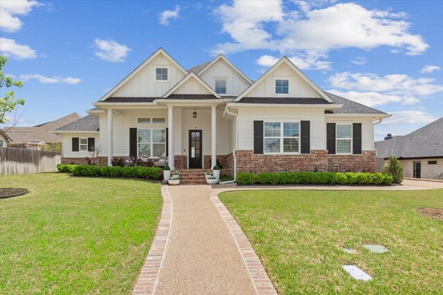 craftsman house with fence, a front lawn, board and batten siding, and brick siding
