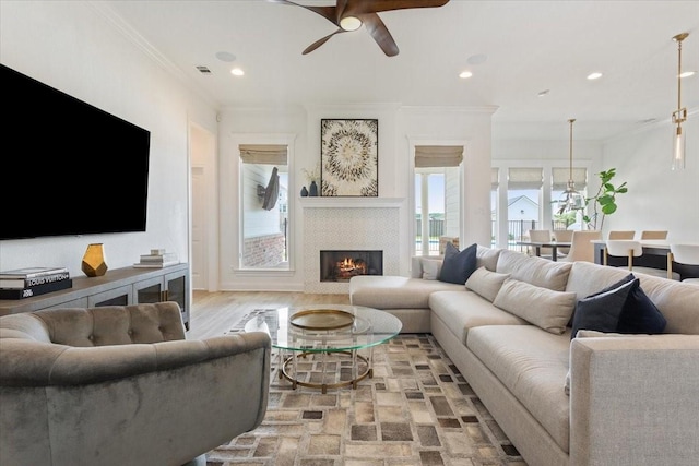 living room featuring crown molding, ceiling fan, visible vents, recessed lighting, and a tiled fireplace