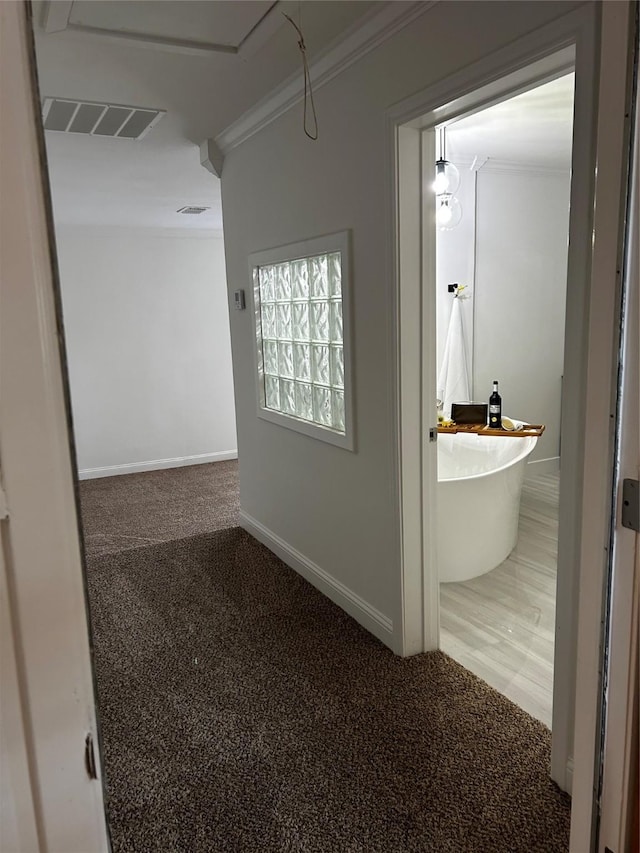 corridor featuring baseboards, ornamental molding, carpet, and visible vents