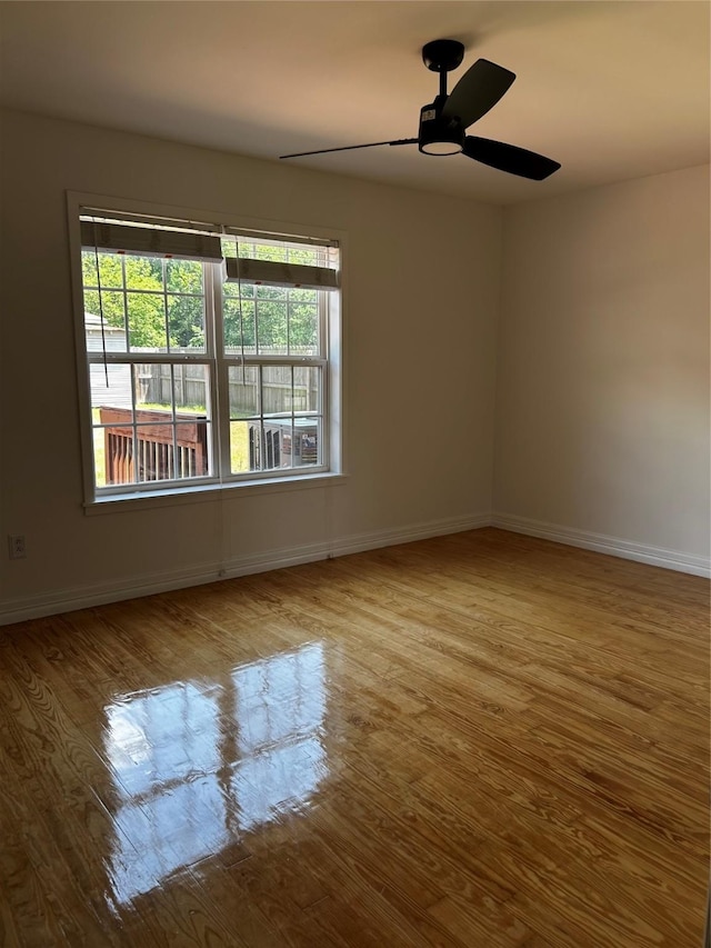 unfurnished room with a ceiling fan, baseboards, and wood finished floors