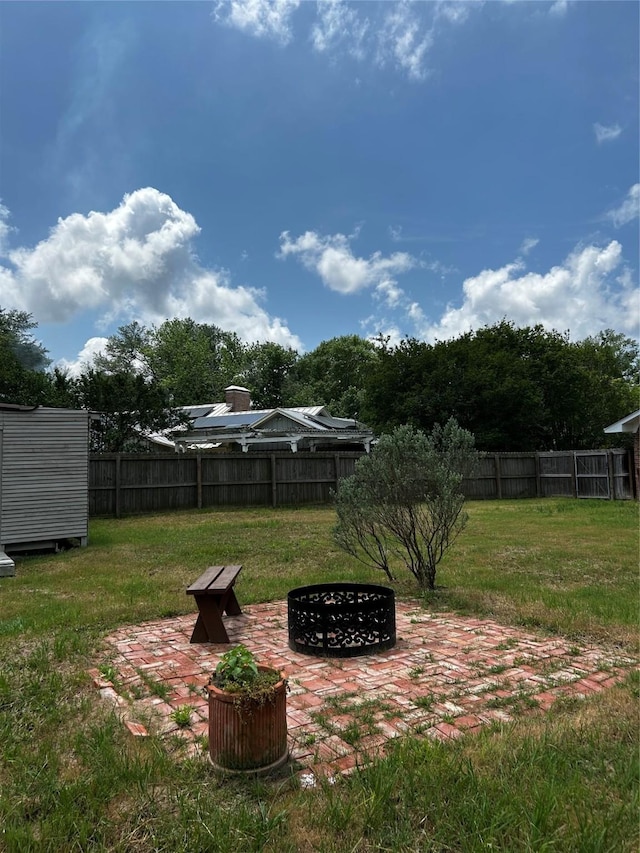 view of yard with fence, a fire pit, and a patio area