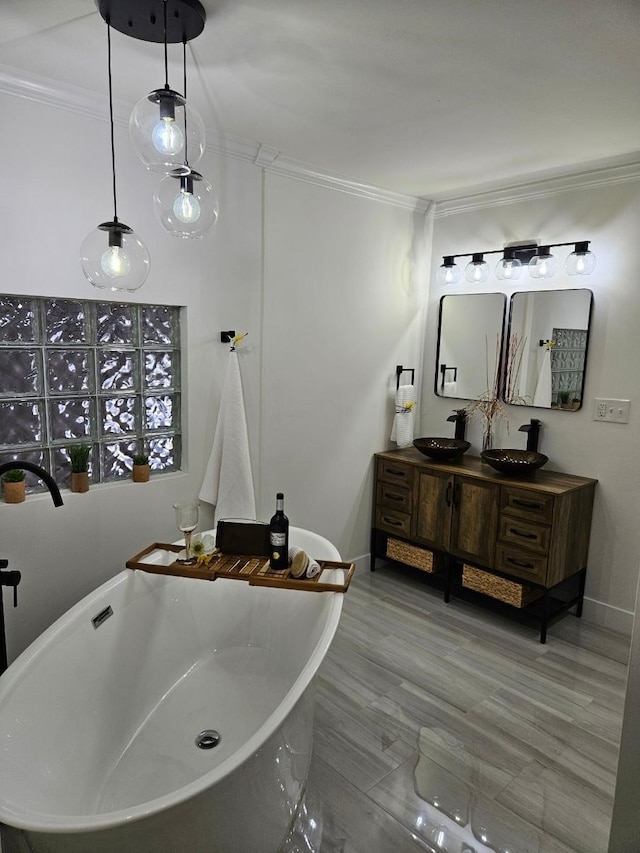bathroom featuring double vanity, ornamental molding, a sink, and a freestanding bath