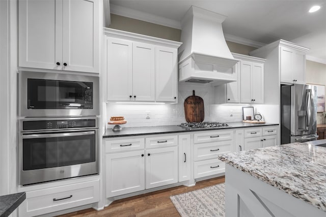 kitchen with crown molding, custom range hood, white cabinetry, and stainless steel appliances