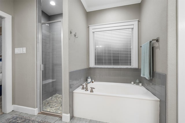 full bath with a stall shower, a garden tub, and crown molding