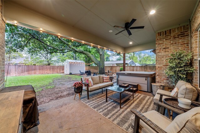view of patio / terrace with a storage unit, ceiling fan, a fenced backyard, and a hot tub