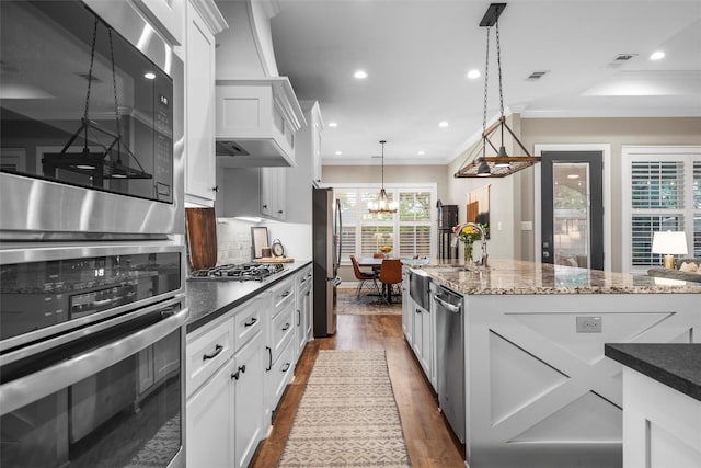 kitchen with a notable chandelier, dark wood-type flooring, backsplash, white cabinets, and appliances with stainless steel finishes