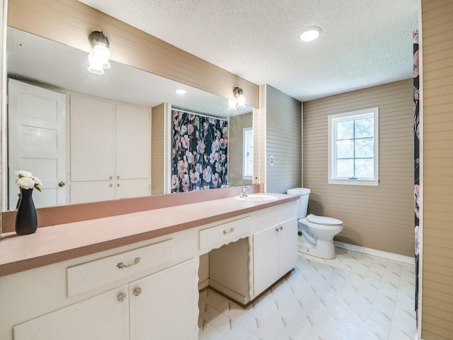 bathroom with vanity, tile patterned floors, toilet, baseboards, and a textured ceiling