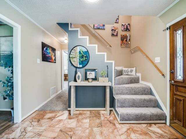 staircase featuring a textured ceiling, visible vents, ornamental molding, and baseboards